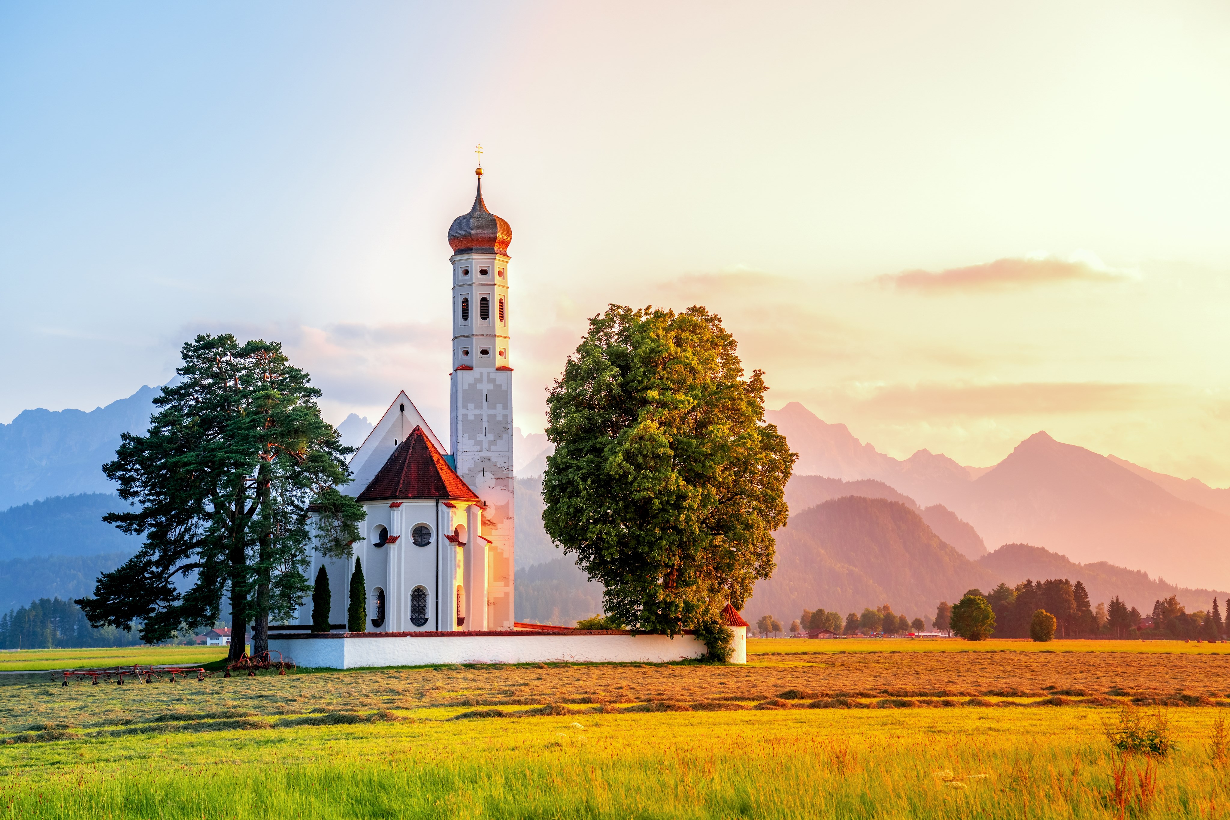 Blick auf Kirche auf Feld mit Bergen im Hintergrund